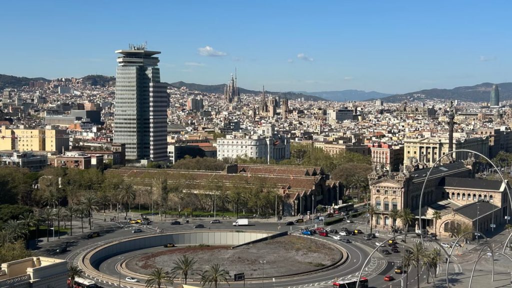 Aerial view of Barcelona showcasing urban skyline with iconic landmarks on a sunny day.