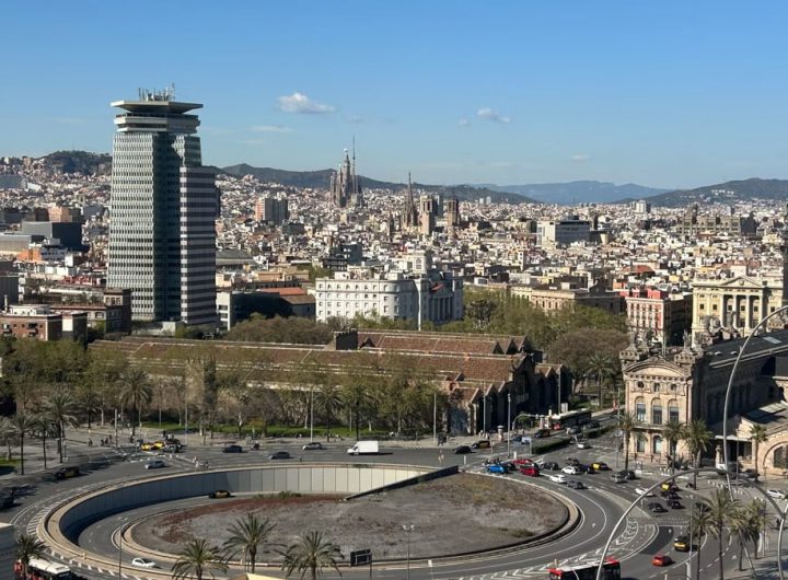 Aerial view of Barcelona showcasing urban skyline with iconic landmarks on a sunny day.